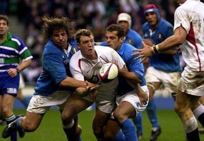 England's Mike Tindall passes the ball despite being tackled duri - Old Photo