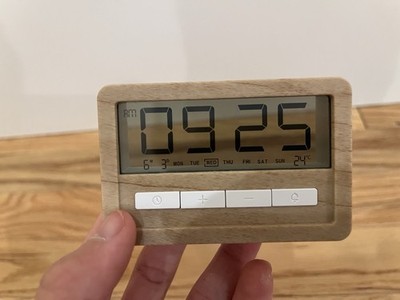 Transparent digital alarm clock that displays time, date, day, and temperature 