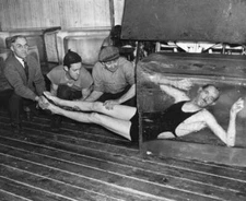 Three men guiding an unspecified endurance artist wearing a swimsu Old Photo