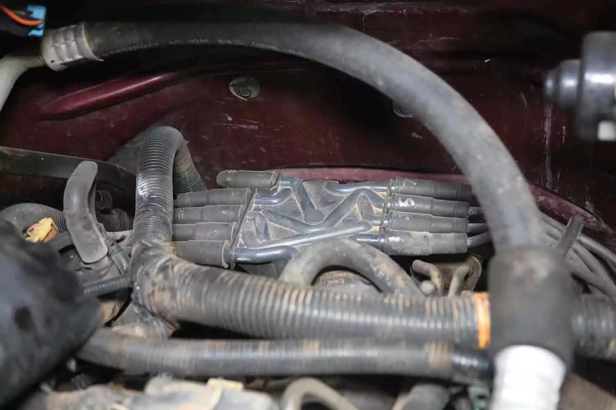 A close-up view of a dusty distributor cap with perimeter plug wires on a V-8 engine.
