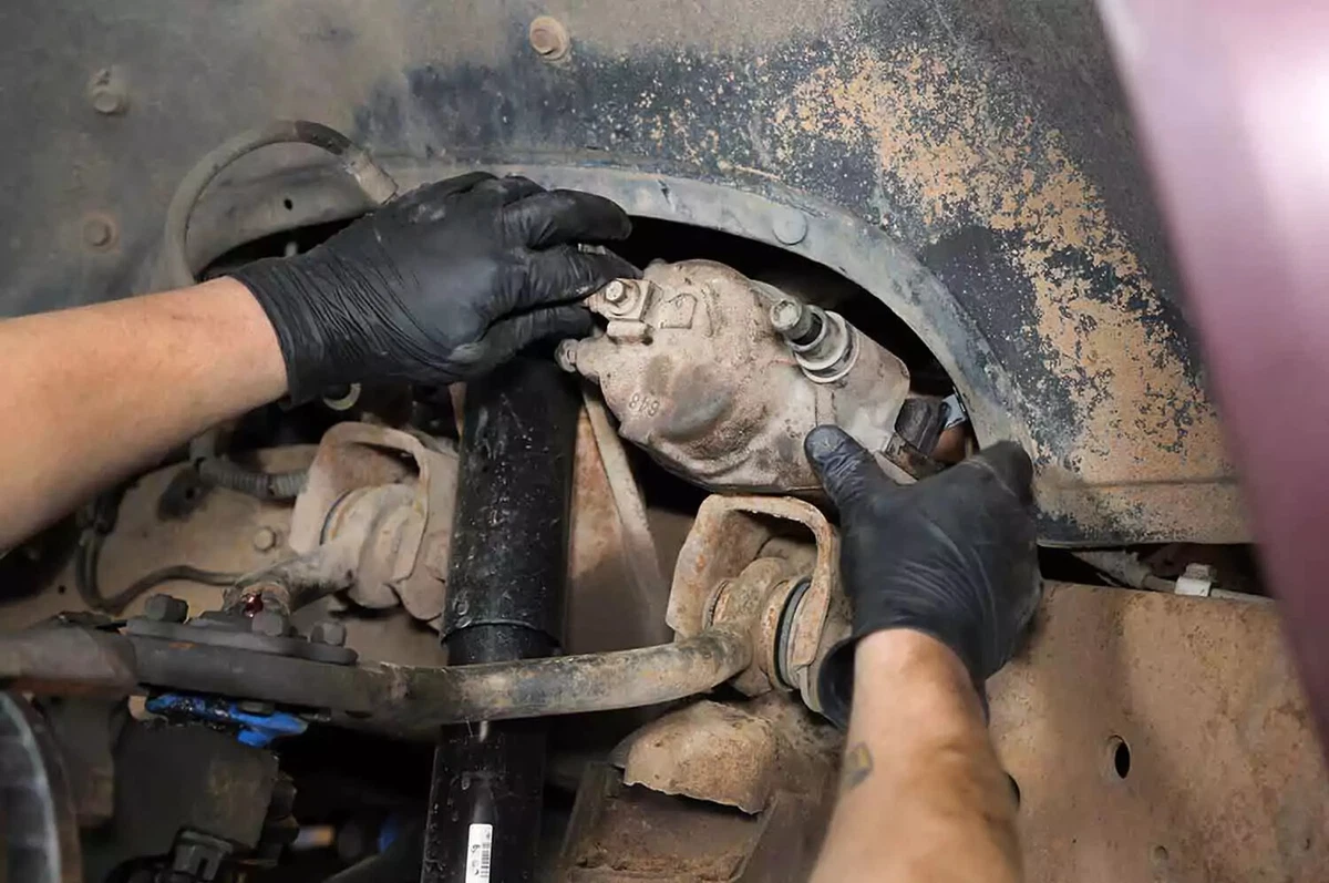 A mechanic places the brake caliper on the truck’s chassis to get it out of the way.