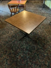 Sturdy square dining table with a wood top and black metal base