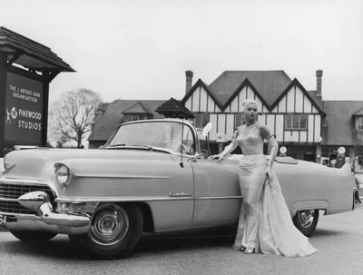 British actor Diana Dors posing next to a Cadillac convertible at - Old Photo