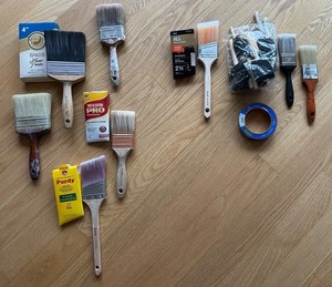 Lot of new and used paint brushes, new roll of blue painter's tape, new foam
