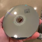 Silver PS3 game case with blue central label, black text “Need for Speed Most Wanted Hot Pursuit Rivals” on brown surface.