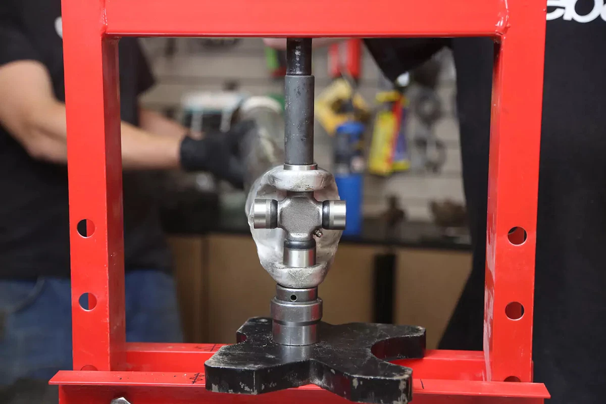 A mechanic uses a press to press the U-joint together.