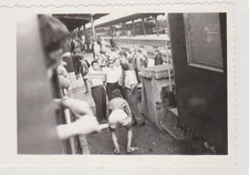 Playful Young Man Bending At The Train Station Surrounded By Laughing Men Photo