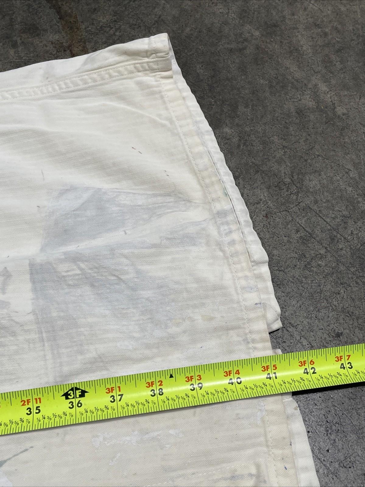 White vintage painters smock work wear canvas coat size 40 with yellow measuring tape across the lower edge.