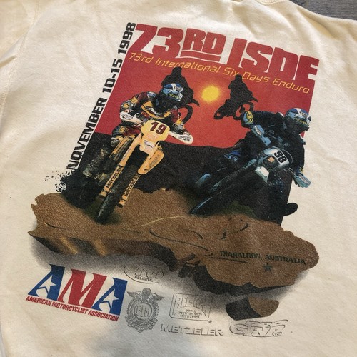 White vintage 1998 pullover sweatshirt with two riders on dirt bikes, red-orange background, and AMA logo.