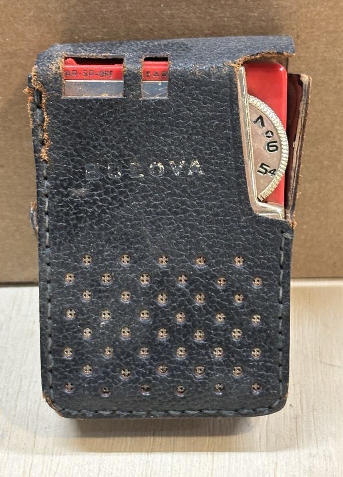 A scarlet red Bulova pocket radio with its original leather case — Bulova made watches, so this crossover gadget is a genuinely surprising collector's piece.