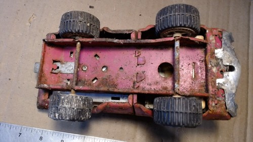 Top view of worn red vintage 1970s Tonka pressed steel pink pick-up truck with visible suspension and interior holes.