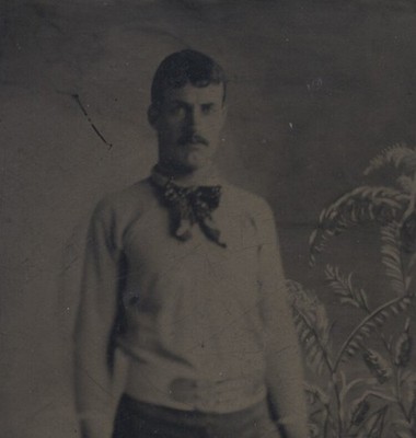 PORTRAIT OF TALL MUSCLE MAN IN RIBBON BOW W/ BARBELLS