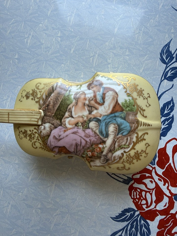 A delicate Sankyo porcelain music box featuring a courting couple with gold floral accents — the kind of heirloom piece grandma had that you now actually want.