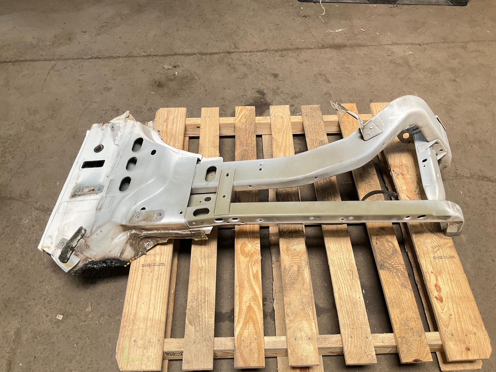 Silver 13-18 RAM 1500 front left driver frame apron radiator support with jagged edges on a wooden pallet.