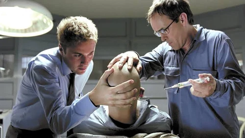 Two men in white lab coats working on a patient head with a needle, text “BEYOND RE-ANIMATOR” at the top.