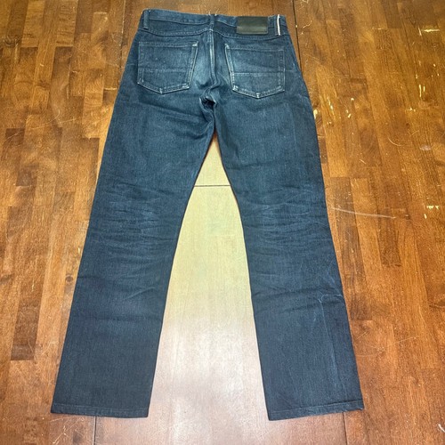 Back view of Gustin men’s 30x29 indigo raw selvedge denim jeans with two pockets and brown leather patch on waistband.