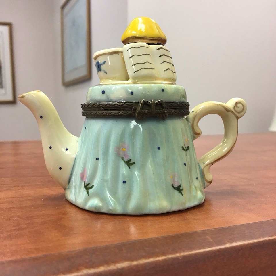 A tiny hand-painted porcelain teapot that secretly opens into a trinket box — the kind of delightful little object that looks like it belongs in a curiosity cabinet.