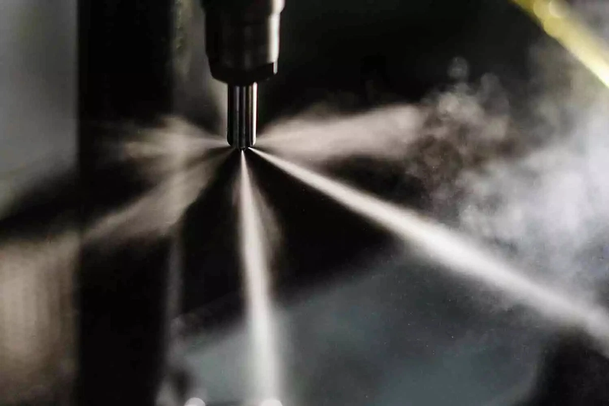 A close-up view of a fuel injector spraying atomized fuel-air mixture in six directions.