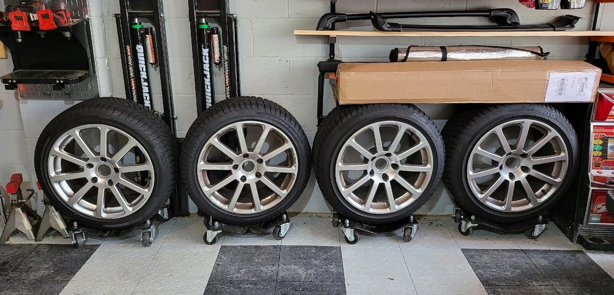 Four wheels with Pirelli tires on wheel dollies in a garage