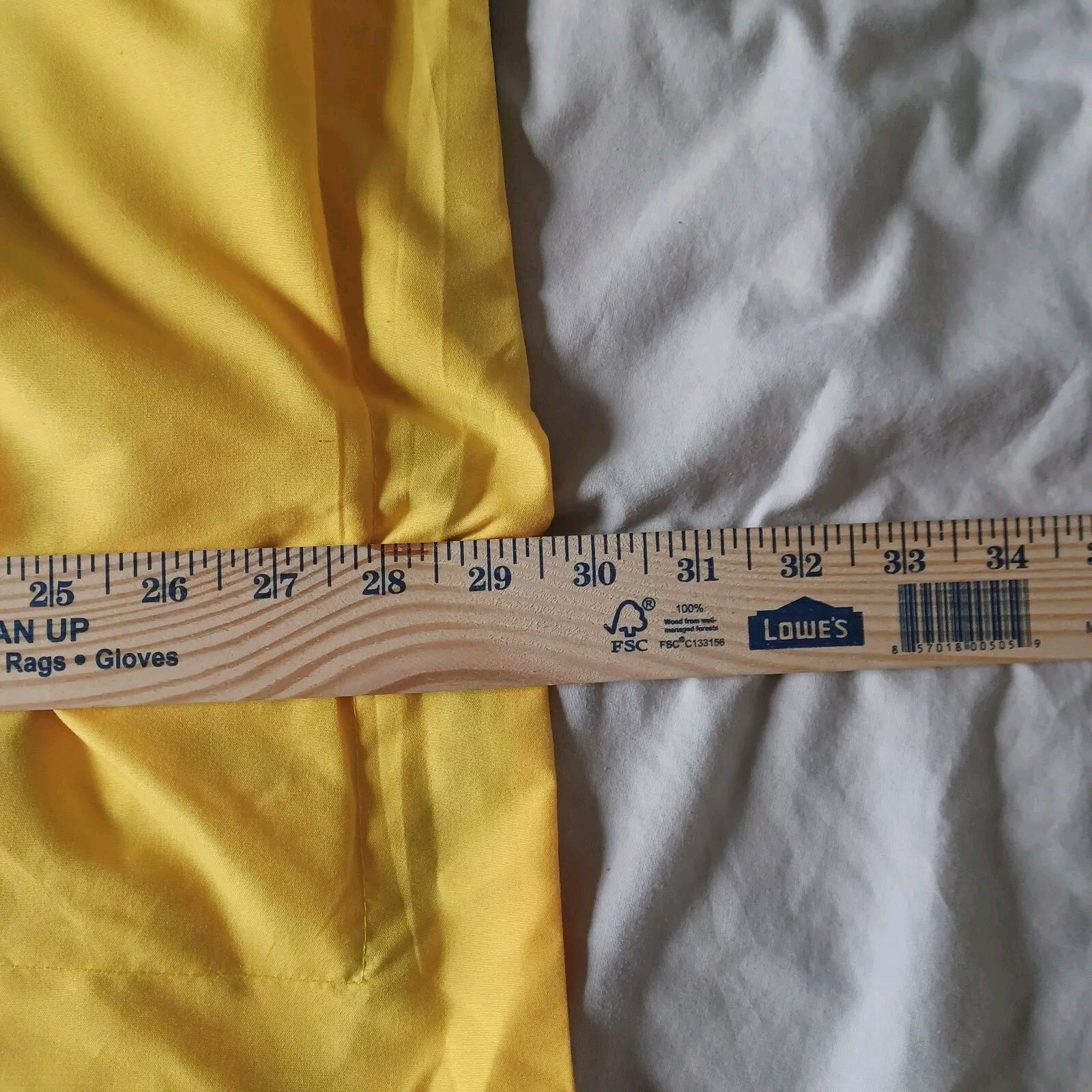 Yellow fabric Golden State Warriors NBA pillow case with black trim, placed on white sheets, next to a wooden ruler for scale.