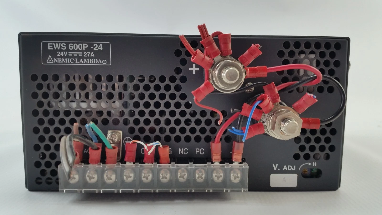 Front panel of the EWS600P-24 with crimped wires on the + and - studs, terminal strip and V.ADJ trimmer
