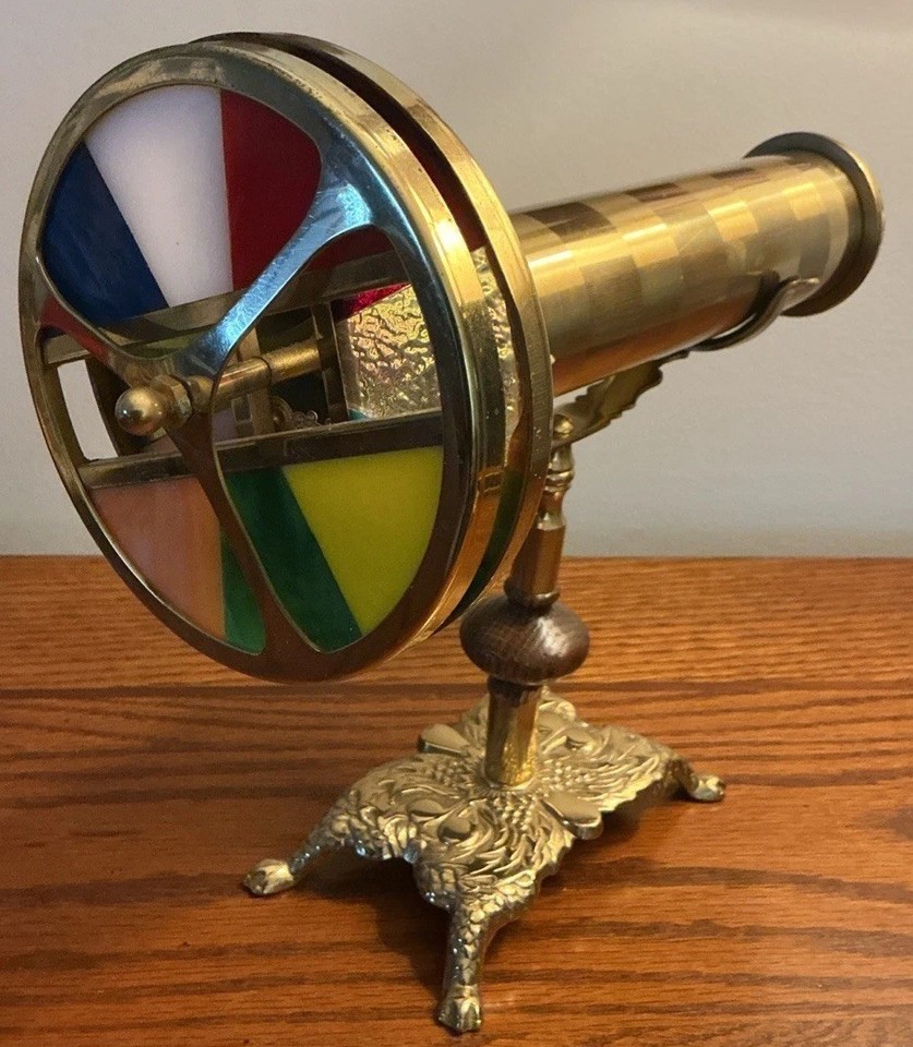 An ornate dual-wheel brass kaleidoscope on a stand with claw feet — basically Victorian optical sculpture that also works as a kaleidoscope.