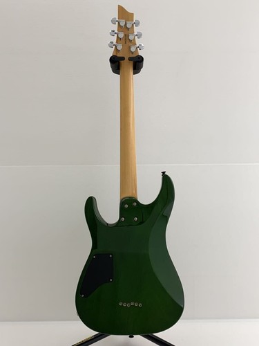 Green SCHECTER PA-SW/TH/See-Thru electric guitar with silver hardware and tapered back on white stand.