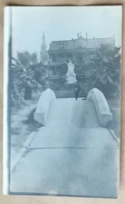 Real photo postcard, man on arched walkway in front of building w/ cross on top