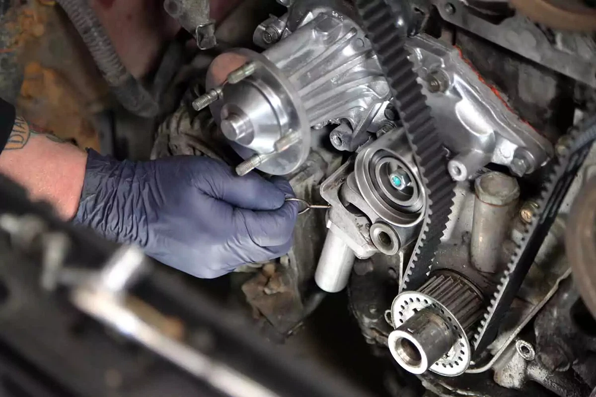 Mechanic pulling the timing belt tensioner pin.