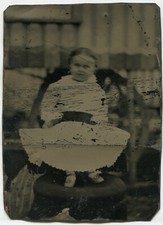 YOUNG CHILD IN DRESS WITH DARK SASH. TINTYPE.