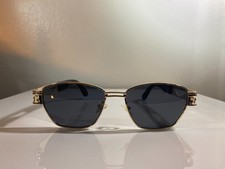 Unisex sunglasses with decorative gold wire frame and black tinted lenses.