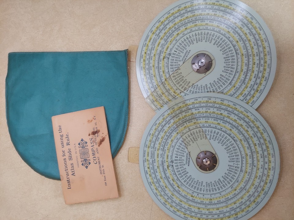 A complete vintage Atlas circular slide rule set with case and instructions — a beautiful pre-digital computing artifact that's also a satisfying mechanical puzzle to use.