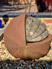 A LARGE ROUNDED RUSTY 3/4 METAL SUPPORT WITH A CORRUGATED CONCRETE INFILL