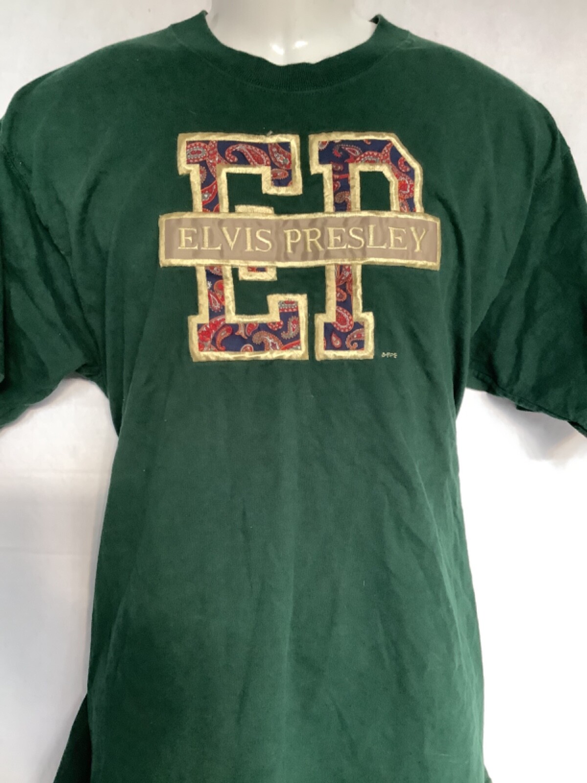 Dark green short-sleeve T-shirt with large beige “ELVIS PRESLEY” text and red paisley pattern across the chest.