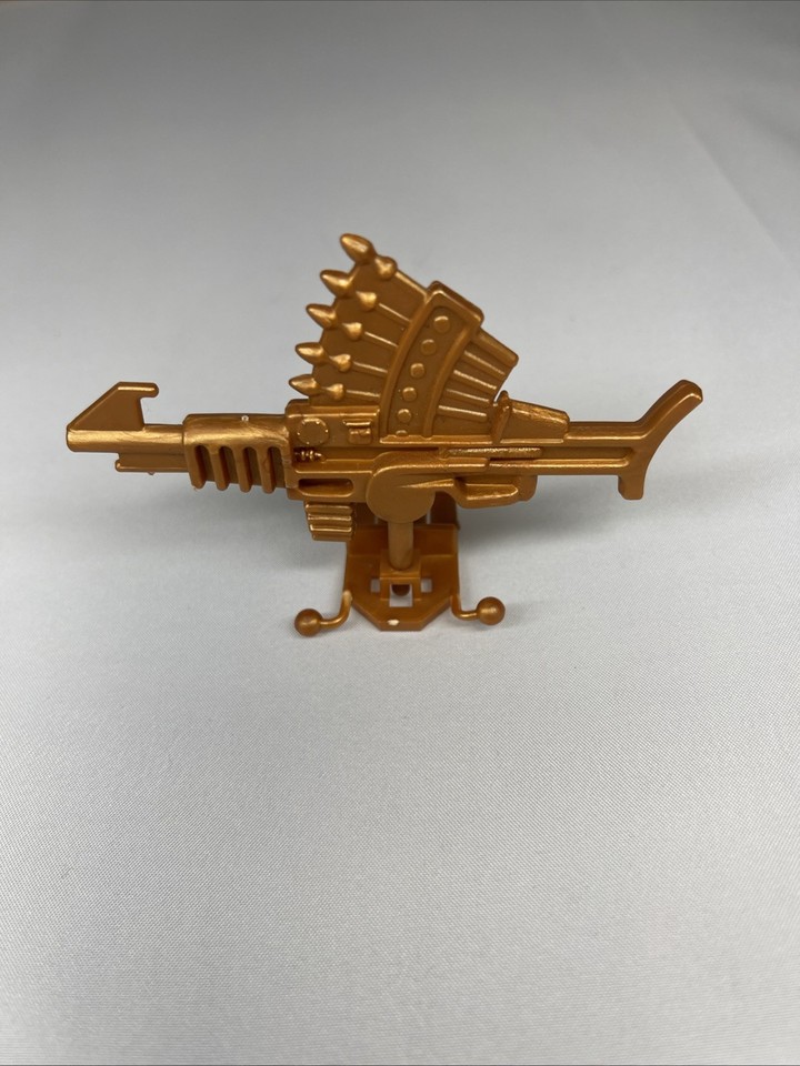 A 1986 Eternia Gold Arrow Dart Gun from MOTU — an obscure, beautifully aged playset accessory that doubles as a conversation-starting vintage desk relic.