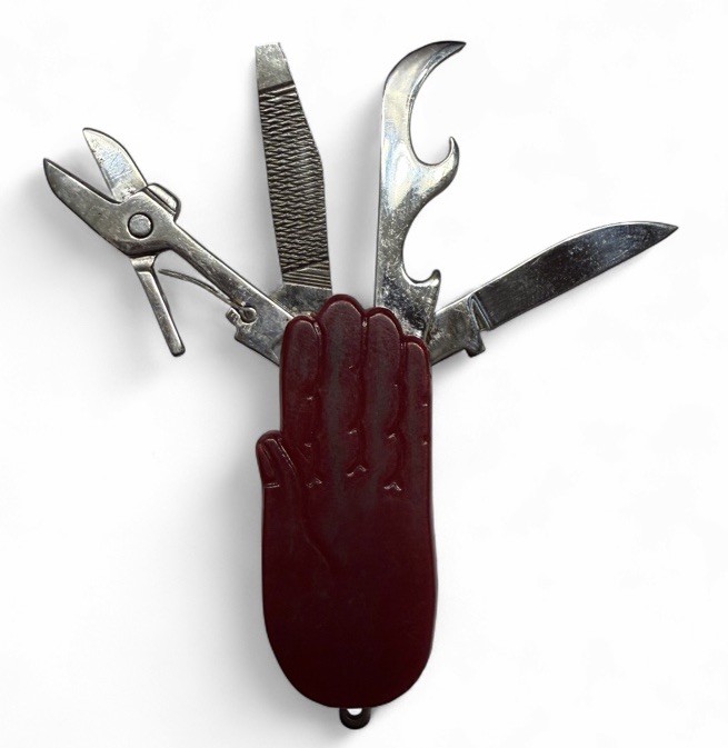 A red novelty folding knife shaped like a hand — weird, kitschy, and instantly giftable for anyone who loves oddball vintage curios.