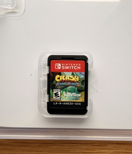 White Nintendo Switch Crash Bandicoot N Sane Trilogy case with colorful mountain and forest scene on front.