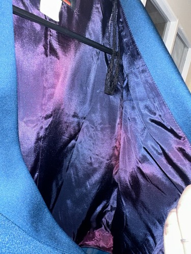 Blue vintage J.R. Nites coat, size 12, with purple and black velvet lining on hanger against white wall.