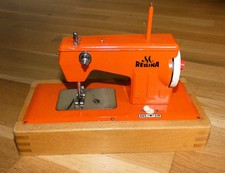 Alte Regina Blech Kindernähmaschine auf Holzsockel, Elektrik läuft