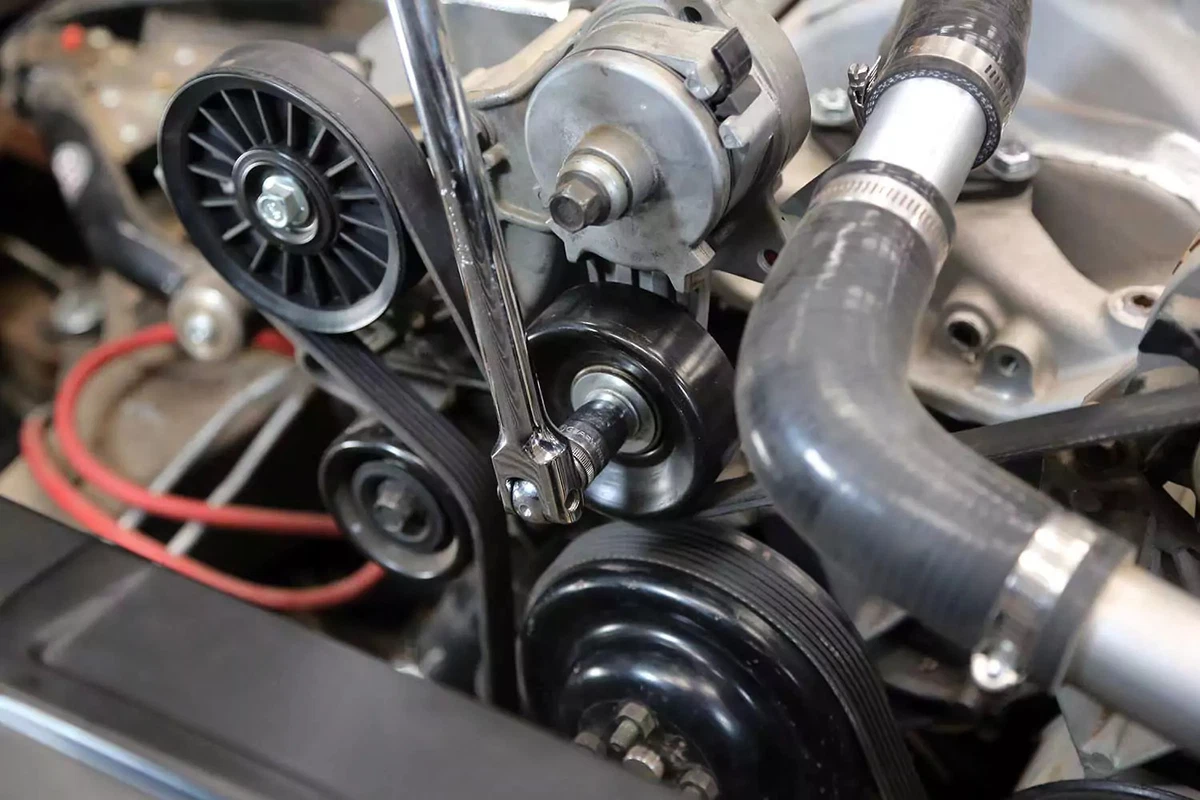 A breaker bar loosens the drive belt tensioner. 