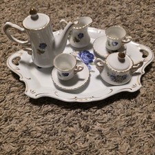 miniature porcelain tea set with a blue floral design and gold gilded edges.