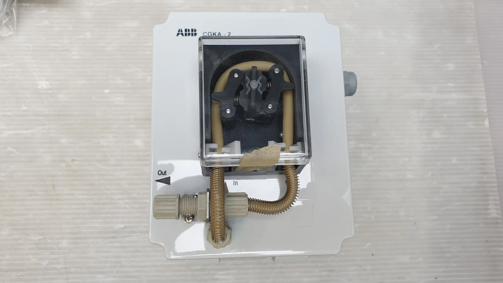 Front of the ABB CGKA-2 with pump head behind clear cover and In/Out ports