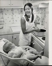 1970 Press Photo Mrs. Casey Lustgarten Watches Baby Lisa While Cooking