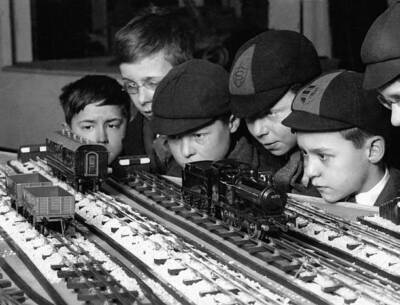 Group of schoolchildren admiring an electric train circuit in an e - Old Photo 1