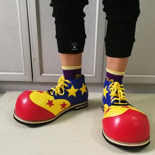 Bright red and blue clown shoes with yellow starbursts, white laces, and “NU AQUAN” label on the side.