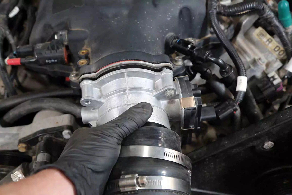 A mechanic installs the new throttle body using a new gasket.
