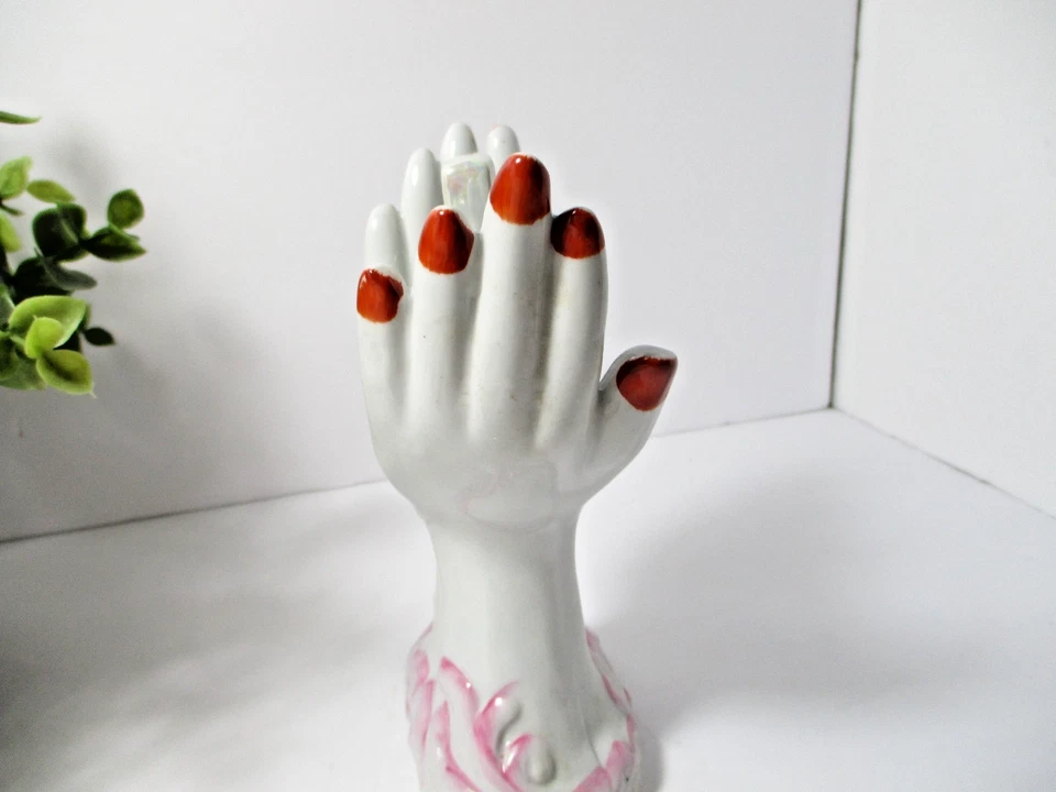 Dos manos de cerámica con clavos rojos sosteniendo una cruz y flores. Foto 4 de 4