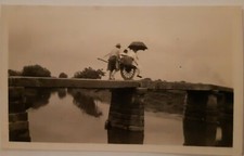 1920s Photo Of Chinese worker Pushing Man in Wheelbarrow Across Narrow Bridge...