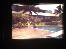 9A02 35MM SLIDE Photo WOMAN STANDS NEAR POOL, MAN CARRYING BOXES