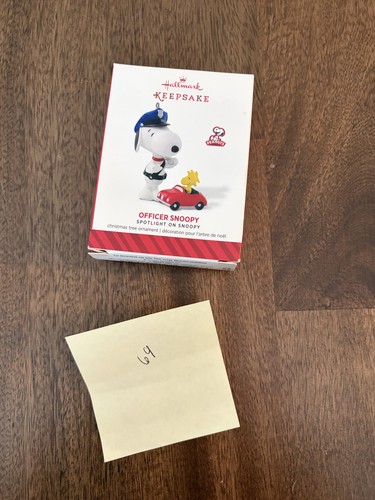 2014 Hallmark Keepsake Officer Snoopy #17 ornament in box with red and green Snoopy graphics and peanut-shaped cookie cutter.
